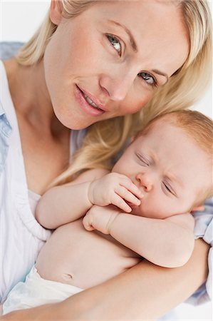 simsearch:6109-06006613,k - Close up of woman holding her sleeping baby against a white background Stock Photo - Premium Royalty-Free, Code: 6109-06006612