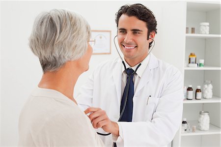 Smiling young doctor taking mature patients heart beat Stock Photo - Premium Royalty-Free, Code: 6109-06006626