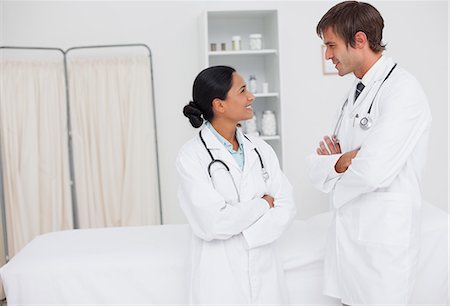 professional medical - Young smiling doctors looking at each other while standing up in a hospital room Stock Photo - Premium Royalty-Free, Code: 6109-06006775