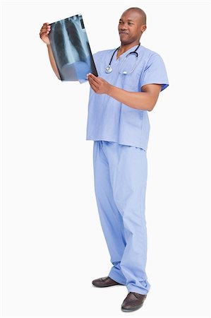 doctor uniform - Doctor in scrubs looking at an x-ray against a white background Foto de stock - Sin royalties Premium, Código: 6109-06006727