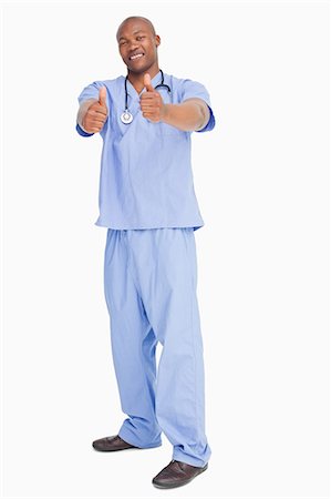 Smiling doctor in scrubs giving his approval against a white background Stock Photo - Premium Royalty-Free, Code: 6109-06006726