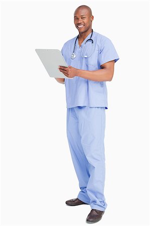 doctor uniform - Smiling doctor in scrubs with a clipboard against a white background Foto de stock - Sin royalties Premium, Código: 6109-06006732