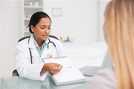 explaining - Serious practitioner pointing her clipboard with a pen while sitting in front of a patient Stock Photo - Premium Royalty-Free, Code: 6109-06006888