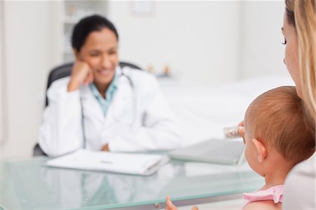 female doctor and child patient - Little baby being held by her mother sitting in front of the practitioner Stock Photo - Premium Royalty-Free, Code: 6109-06006895