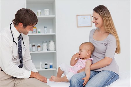 Smiling mother holding her little baby while sitting in front of the doctor in his office Stock Photo - Premium Royalty-Free, Code: 6109-06006956
