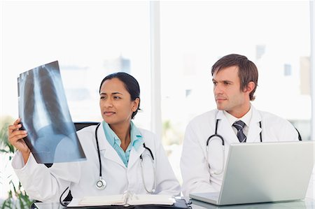 simsearch:6109-06006911,k - Serious doctors sitting at a desk in front of a laptop while looking at a chest x-ray Fotografie stock - Premium Royalty-Free, Codice: 6109-06006998