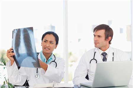 Doctor holding and pointing at an x-ray while talking to her colleague Stock Photo - Premium Royalty-Free, Code: 6109-06006999