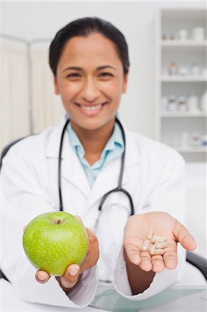 Beautiful green apple and vitamins being held by a nutritionist Stock Photo - Premium Royalty-Free, Code: 6109-06006929