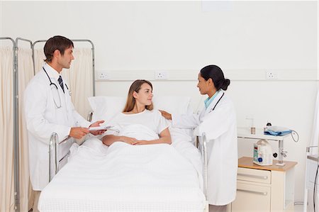 Calme patient couché dans un lit d'hôpital, tout en étant accompagné par deux chirurgiens Photographie de stock - Premium Libres de Droits, Code: 6109-06007047