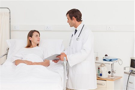 seriously ill patient - Relaxed patient lying in a bed while talking to her doctor who is holding a clipboard Stock Photo - Premium Royalty-Free, Code: 6109-06007050