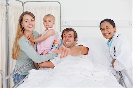 sick patients hugging - Happy man pointing the camera while being surrounded by his family and a doctor Foto de stock - Sin royalties Premium, Código: 6109-06007066