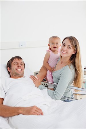 sick people in bed mans - Happy patient lying in a hospital bed while his smiling family is standing next to him Stock Photo - Premium Royalty-Free, Code: 6109-06007070