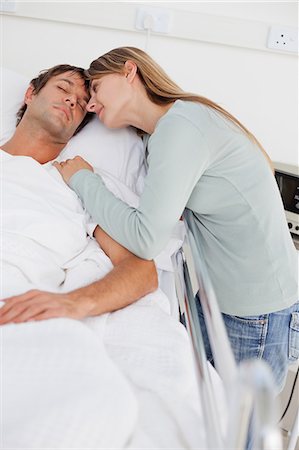 sleeping couple on the bed - Patient sleeping in a hospital bed while his wife is placing her head next to him Foto de stock - Sin royalties Premium, Código: 6109-06007076