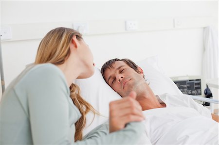 sick people in the hospital - Peaceful patient sleeping in a hospital bed while his lovely wife is looking at him Stock Photo - Premium Royalty-Free, Code: 6109-06007079