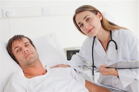 A patient and a doctor looking at the camera while staying in a hospital bedroom Foto de stock - Sin royalties Premium, Código: 6109-06007088