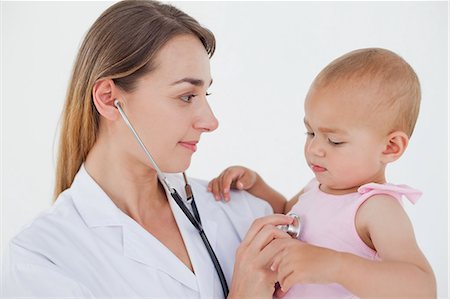 pediatrician stethoscope - Doctor looking at the lovely baby while holding and auscultating her Stock Photo - Premium Royalty-Free, Code: 6109-06007095