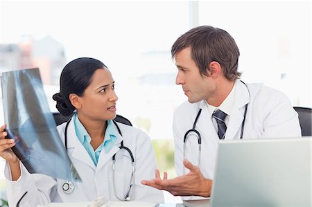 simsearch:6109-06006905,k - Serious doctors talking to each other about a chest x-ray while sitting at a desk Stock Photo - Premium Royalty-Free, Code: 6109-06007002