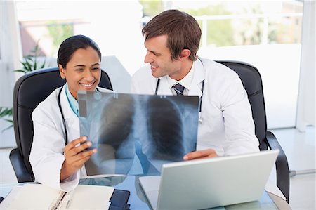 simsearch:6109-06006911,k - Smiling surgeons holding a chest x-ray while sitting down Fotografie stock - Premium Royalty-Free, Codice: 6109-06007006