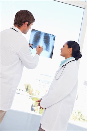 simsearch:6109-06006911,k - Rear view of a doctor holding and looking at an x-ray with a colleague Fotografie stock - Premium Royalty-Free, Codice: 6109-06007016