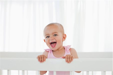 Little baby shouting loudly while standing up in her bed Fotografie stock - Premium Royalty-Free, Codice: 6109-06007023