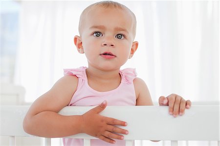 Little baby trying to get out of her bed while looking away Stock Photo - Premium Royalty-Free, Code: 6109-06007021