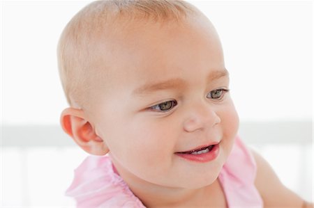 Baby looking towards the side while showing a great smile Stock Photo - Premium Royalty-Free, Code: 6109-06007029