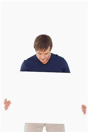 Homme calme tenant une affiche vide tout en penchant la tête contre un fond blanc Photographie de stock - Premium Libres de Droits, Code: 6109-06007152