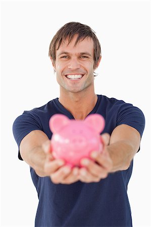 simsearch:6109-06007163,k - Smiling man holding a pink piggy bank against a white background Fotografie stock - Premium Royalty-Free, Codice: 6109-06007158