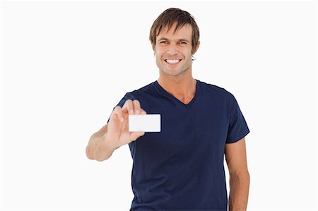 Smiling man holding a blank business card against a white background Fotografie stock - Premium Royalty-Free, Codice: 6109-06007167