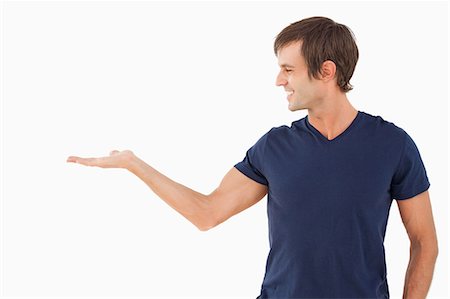 raised - Smiling man standing upright with hand palm up against a white background Stock Photo - Premium Royalty-Free, Code: 6109-06007110