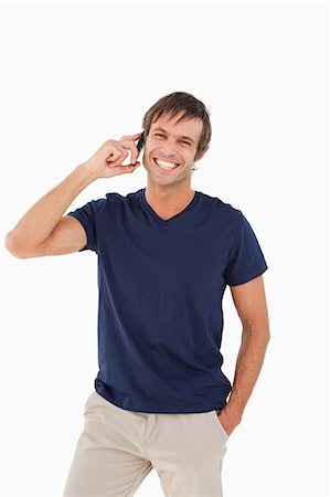 simsearch:6109-06007124,k - Relaxed man standing up with his hands in his pockets while using his mobile phone Stock Photo - Premium Royalty-Free, Code: 6109-06007118