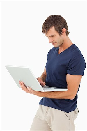 simsearch:6109-06007150,k - Serious man holding a laptop against a white background Foto de stock - Sin royalties Premium, Código: 6109-06007132