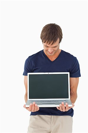 se distinguer - Homme décontracté montrant un ordinateur portable tout en regardant sur un fond blanc Photographie de stock - Premium Libres de Droits, Code: 6109-06007136