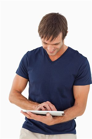 simsearch:6109-06007150,k - Smiling man using his tablet computer while standing up against a white background Foto de stock - Sin royalties Premium, Código: 6109-06007138