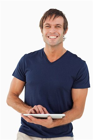 Homme souriant, à l'aide d'une tablette PC tout en levant et en regardant la caméra Photographie de stock - Premium Libres de Droits, Code: 6109-06007139