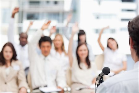 Businessman looking ahead as he gives a speech to his colleagues who have their arms raised Stock Photo - Premium Royalty-Free, Code: 6109-06007240