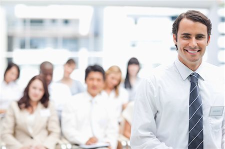 simsearch:6109-06007245,k - Smiling businessman looking ahead as his colleagues sit behind him Foto de stock - Sin royalties Premium, Código: 6109-06007244