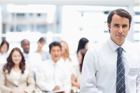 rendez-vous - Homme d'affaires de l'avenir avec une expression sérieuse comme ses collègues assis derrière lui Photographie de stock - Premium Libres de Droits, Code: 6109-06007245