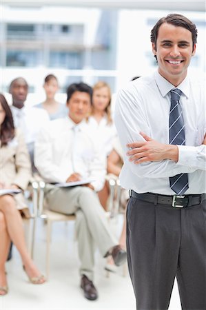 Businessman smiling with his arms crossed as he stands in front of his colleagues Stock Photo - Premium Royalty-Free, Code: 6109-06007250