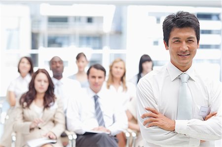 simsearch:6109-06007245,k - Businessman smiling and crossing his arms while standing in front of his colleagues Foto de stock - Sin royalties Premium, Código: 6109-06007252