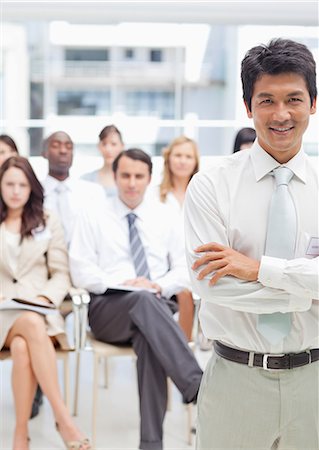 simsearch:6109-06007245,k - Businessman with his arms crossed while his colleagues stand behind him Foto de stock - Sin royalties Premium, Código: 6109-06007256