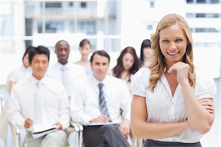 simsearch:6109-06007245,k - Smiling businesswoman looking ahead of her while resting her chin on her hand as she stands in front of her colleagues Foto de stock - Sin royalties Premium, Código: 6109-06007266