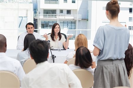 Woman standing while speaking to two business people who are gesturing towards her Stock Photo - Premium Royalty-Free, Code: 6109-06007284