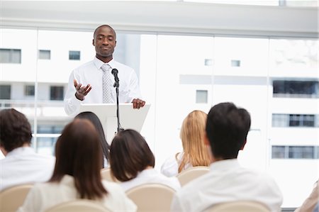 simsearch:6109-06007245,k - Businessman gesturing with his hand towards an audience who are watching him Foto de stock - Sin royalties Premium, Código: 6109-06007297