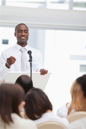 Close-up of a businessman as he gestures towards an audience who is watching him Stock Photo - Premium Royalty-Free, Code: 6109-06007299