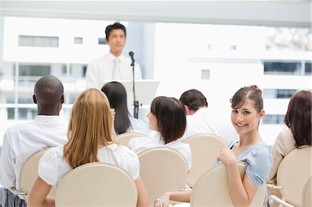 speaker - Business woman with a happy expression looking behind her during a speech Foto de stock - Sin royalties Premium, Código: 6109-06007317