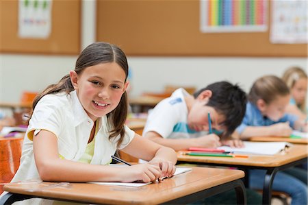 reading in class - Side view of smiling schoolgirl with her exercise book Foto de stock - Sin royalties Premium, Código: 6109-06007460