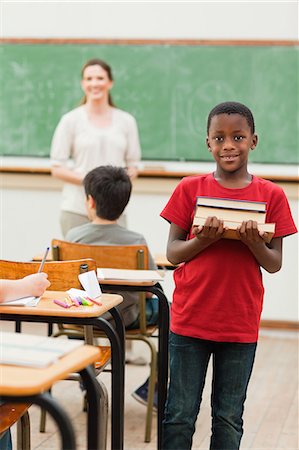 simsearch:6109-06007580,k - Smiling elementary student holding stack of books Foto de stock - Sin royalties Premium, Código: 6109-06007549