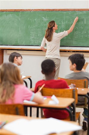 students arms raise - Elementary teacher writing math problems on blackboard Stock Photo - Premium Royalty-Free, Code: 6109-06007529