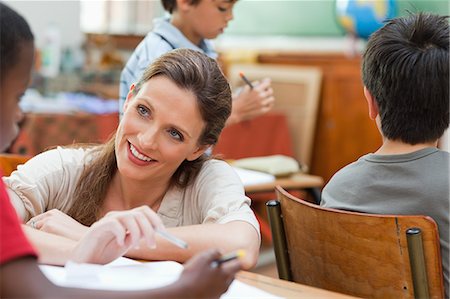 picture of student helping teacher - Smiling elementary teacher talking to one of her students Stock Photo - Premium Royalty-Free, Code: 6109-06007535